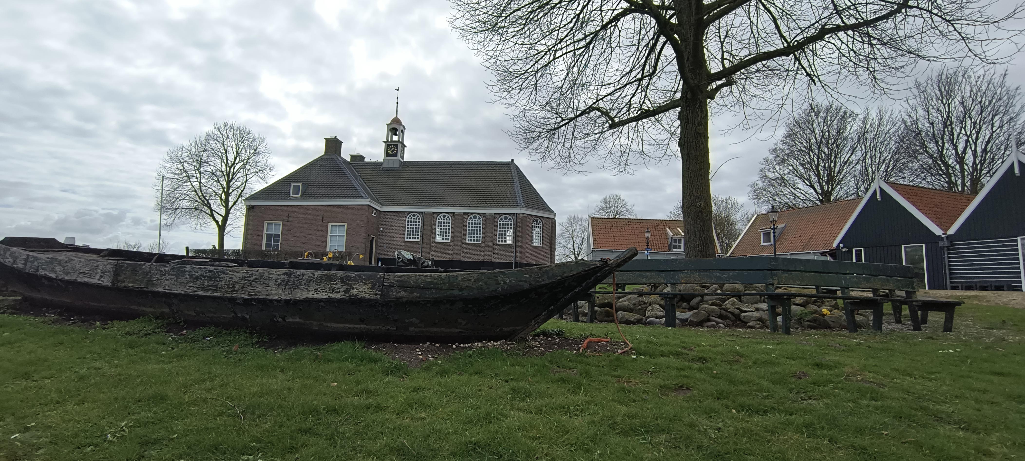 Blick auf dem Gelände von das ehemalige Insel Schokland, das erste Weltkulturerbe der Niederlande, dieses Jahr 30 Jahre.
Grauer Himmel, kleine Kirche, und im Vordergrund ein kleines Schiffchen auf dem Wiese.